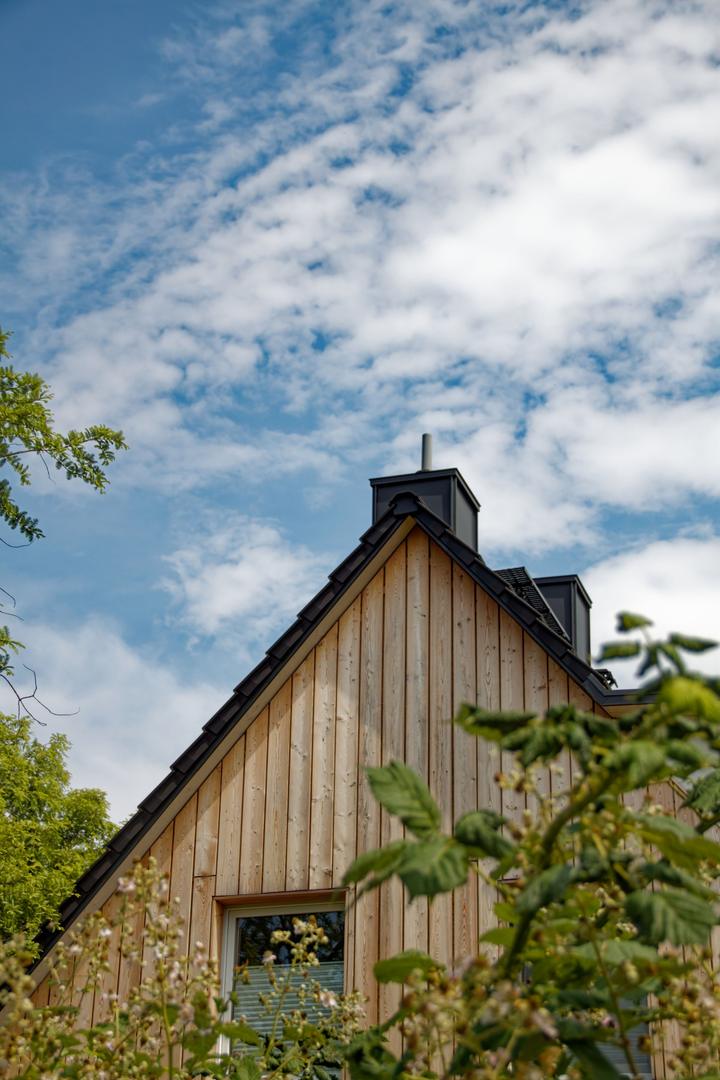 Chimney rising above a timber-clad house under a blue sky