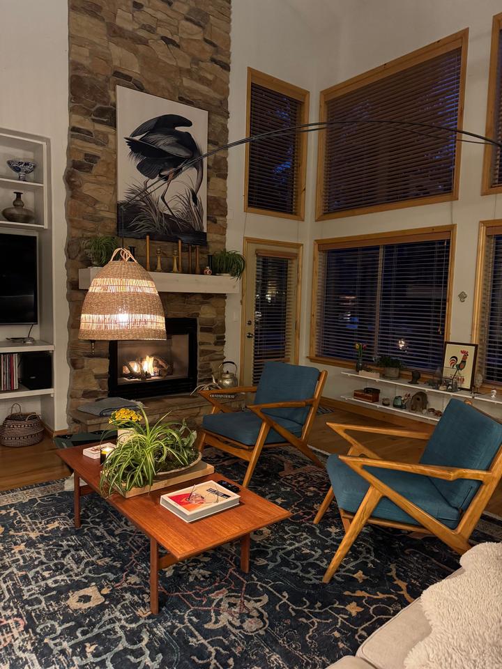 Stone fireplace beside tall windows in a furnished sitting room